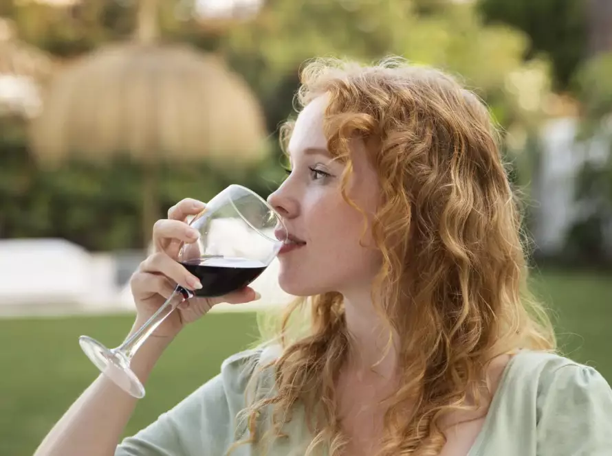Mujer disfrutando de una copa de vino natural en un jardín