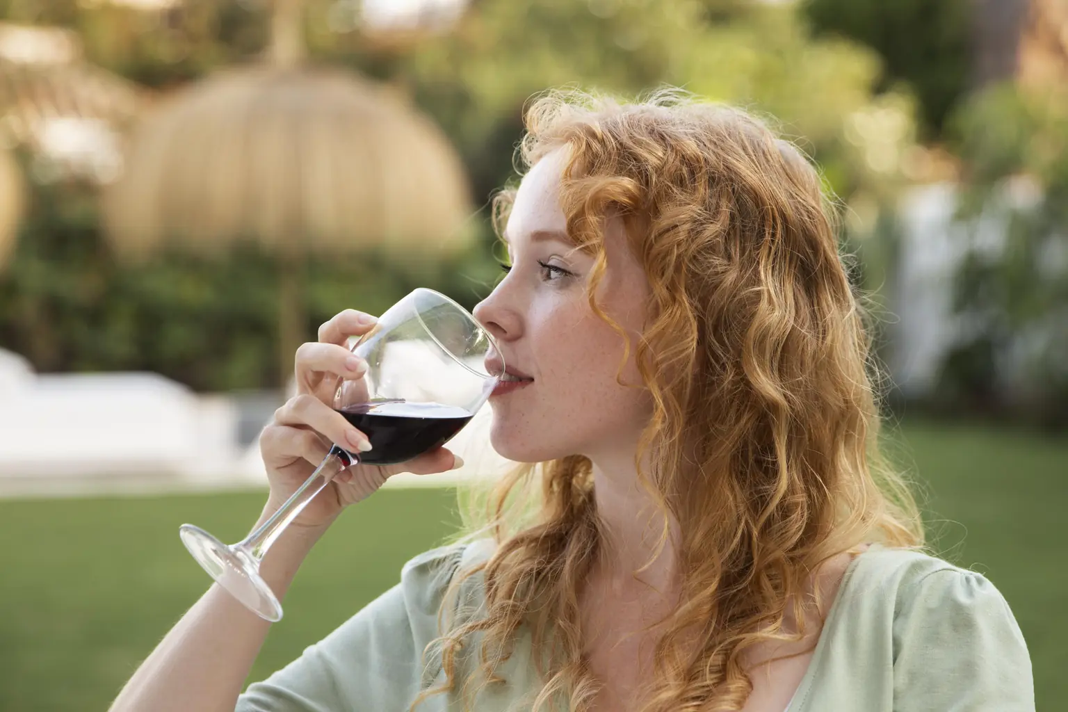 Mujer disfrutando de una copa de vino natural en un jardín